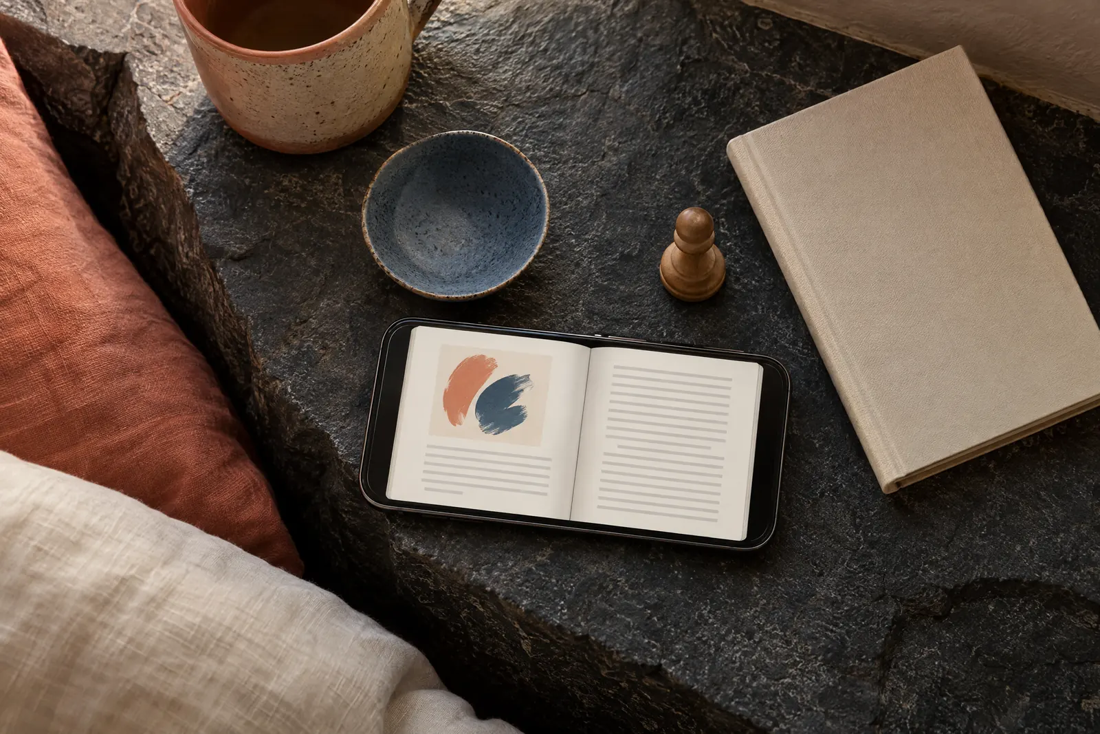 A bedroom alcove still life of a ebook product arranged with a wooden chess pawn, in coral, sand, slate, and cream.