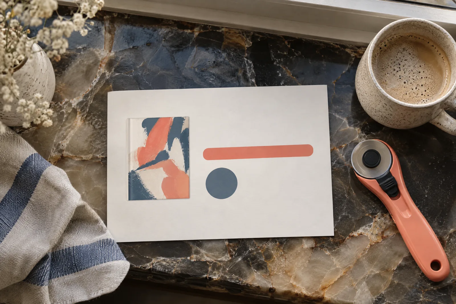 A cafe window still life of a general product arranged with a rotary cutter, in coral, sand, slate, and cream.