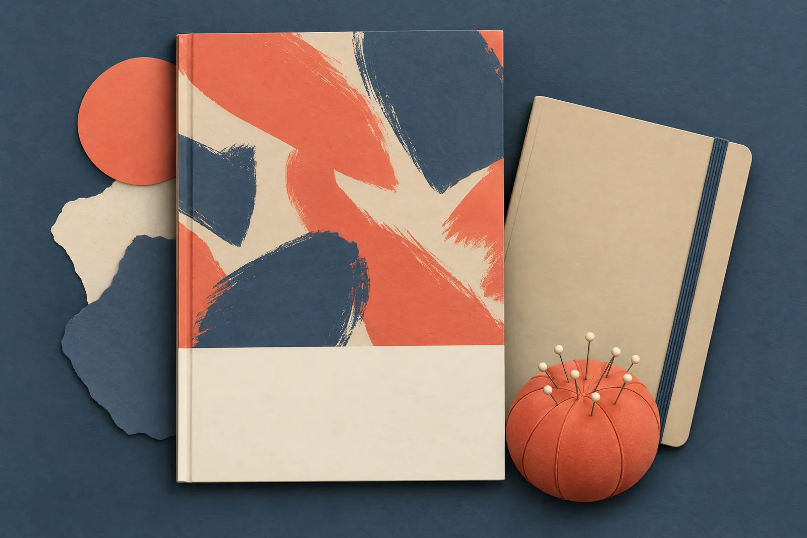 A covered porch still life of a ebook product arranged with a round pin cushion, in coral, sand, slate, and cream.