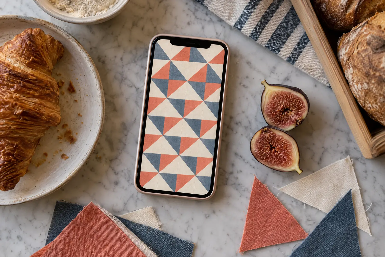 A bakery side counter still life of a craft product arranged with a split fig, in coral, sand, slate, and cream.